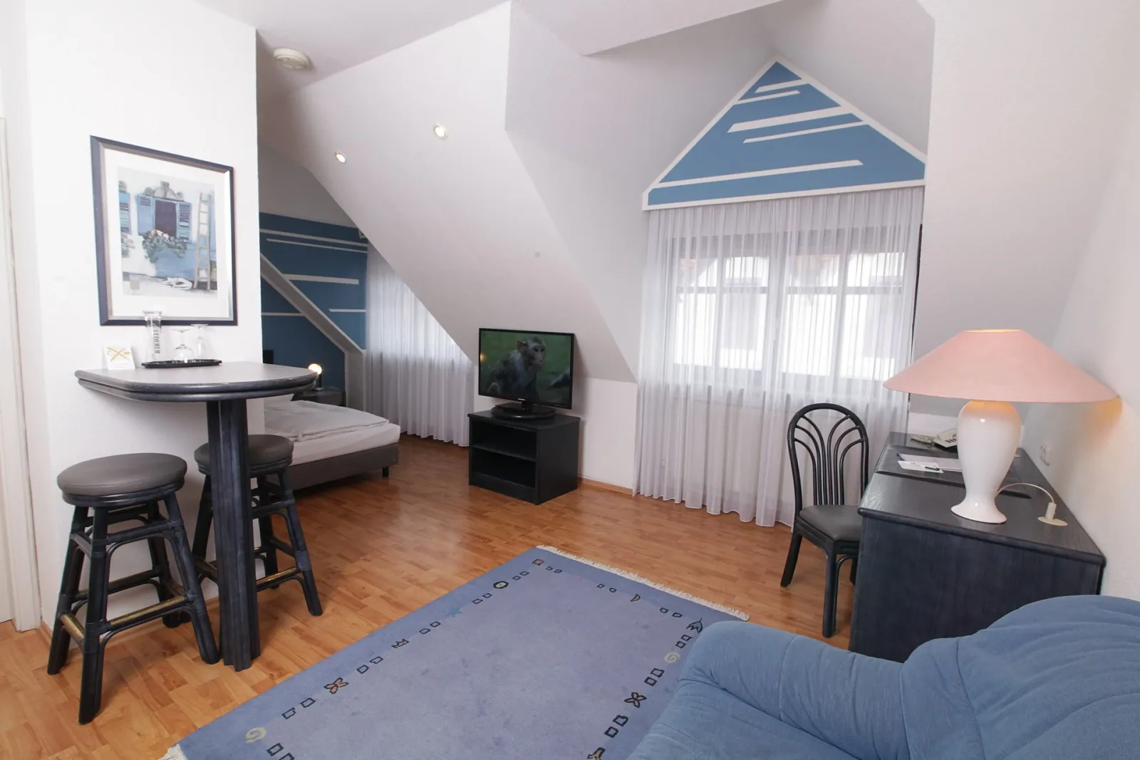 Wohnbereich unter dem Dach mit Sofa, Stehtisch und Fernseher im Art-Hotel Erlangen