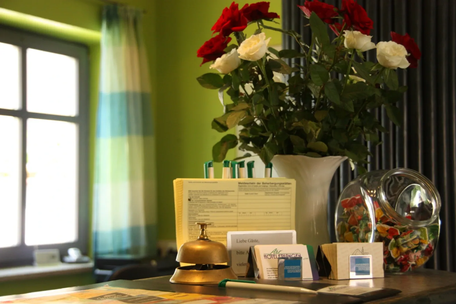 Rezeption des Art-Hotels Erlangen mit Glocke und Blumen